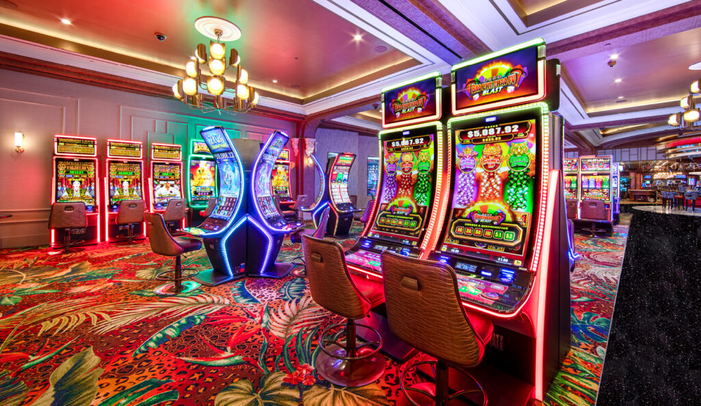 The brightly lit casino, with its colorful slot machines and patterned carpets, intertwines a sense of history with modernity through its sleek chairs and contemporary overhead lights.