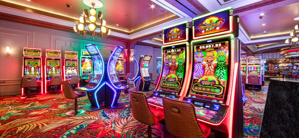 A brightly lit casino filled with colorful slots and patterned carpet, empty chairs inviting players to try their luck.